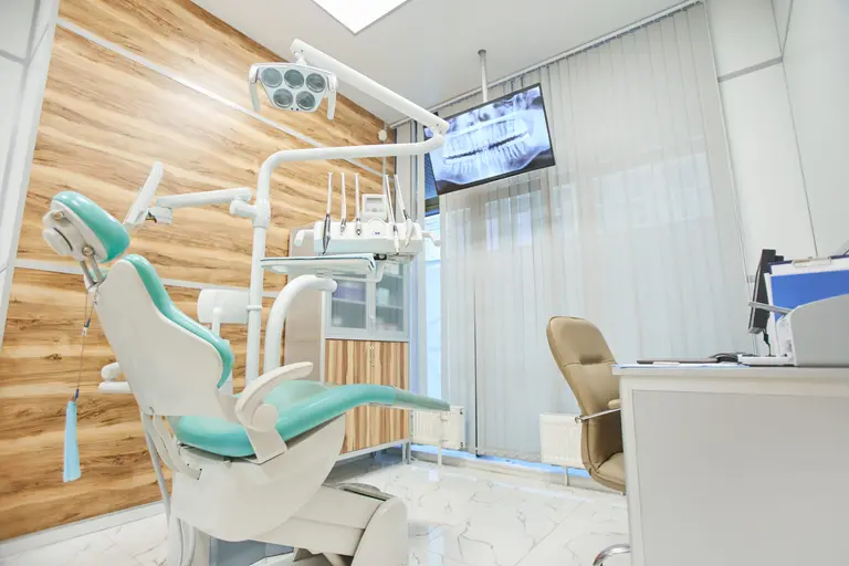Salle de soins lumineuse du cabinet avec fauteuil dentaire et paroi en bois
