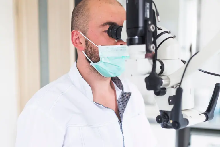 Un médecin-dentiste examine les dents d’une patiente au microscope opératoire