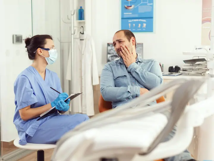 Une assistante dentaire écoute un patient qui lui pose ses questions